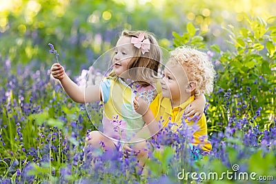 Kids playing in blooming garden with bluebell flowers Stock Photo