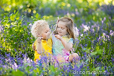 Kids playing in blooming garden with bluebell flowers Stock Photo