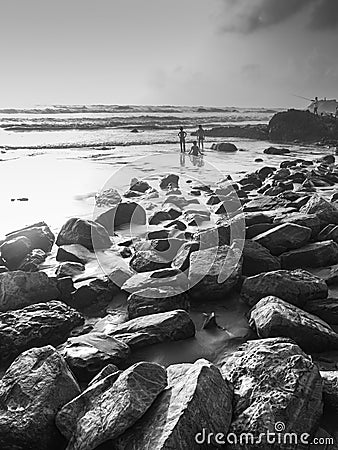 Kids playing in Goa seashore featuring rocks and sea in Black and white Stock Photo