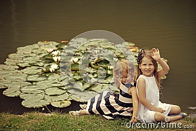 Kids playing - happy game. Girl wave hand at pond with water lily flowers Stock Photo