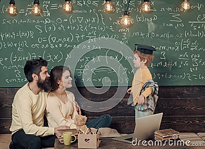 Kids playing - happy game. Homeschooling concept. Smart child in graduate cap likes to study. Parents teaching kid at Stock Photo