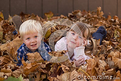 Kids playing in leaf pile leaves Stock Photo
