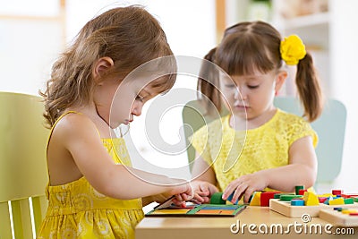 Kids playing with logical toy on desk in nursery room or kindergarten. Children arranging and sorting shapes, colors and Stock Photo