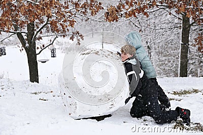 Kids Playing Outside in the Snow and Making a Huge Snowball Stock Photo