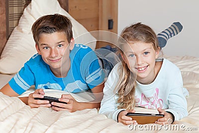 Kids playing with smartphone on a bed Stock Photo