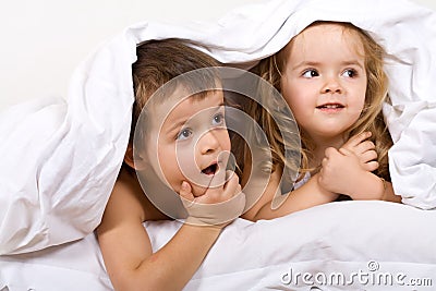 Kids playing under the quilt in bed Stock Photo