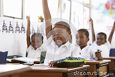 Kids raising hands during a lesson at an elementary school Stock Photo