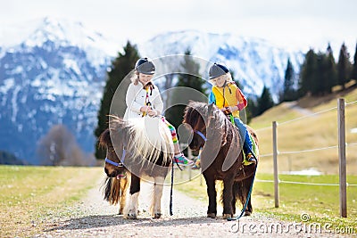 Kids riding pony. Child on horse in Alps mountains Stock Photo