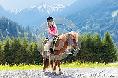 Kids riding pony. Child on horse in Alps mountains Stock Photo