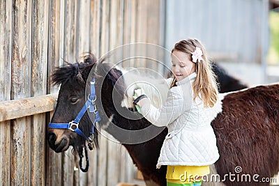 Kids riding pony. Child on horse in Alps mountains Stock Photo