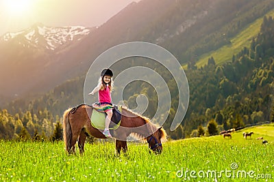 Kids riding pony. Child on horse in Alps mountains Stock Photo
