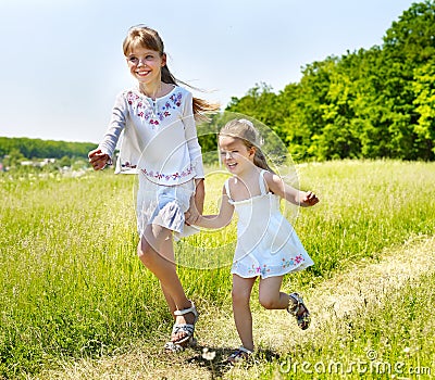 Kids running across green grass outdoor. Stock Photo