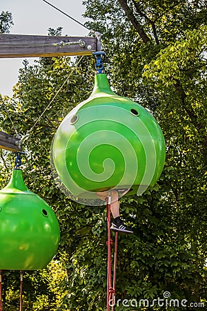 Kids shoes and dirty legs hang out of a lime green climbing pod with rope ladder at Gathering Place public park in Tulsa OK - Editorial Stock Photo