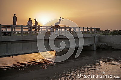 Kids Sitting Water From A Bridge During Sunset, In Moro Editorial Stock Photo