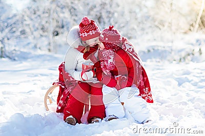 Kids sledding in winter forest. Children drink hot cocoa in snow Stock Photo