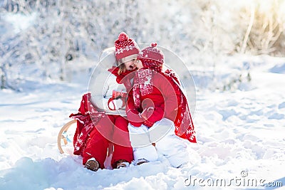 Kids sledding in winter forest. Children drink hot cocoa in snow Stock Photo