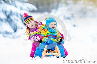 Kids on sleigh ride. Children sledding. Winter snow fun. Stock Photo