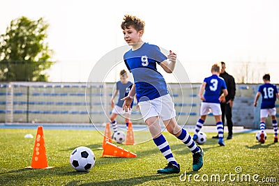 Kids Sports: Teaching Children to Improve Soccer Skills. Football camp for kids. Boys practice dribbling in field Stock Photo