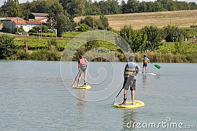 kids on a stand paddle on the pond of the leisure center of Jonzac Editorial Stock Photo