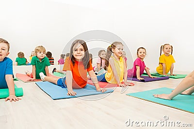 Kids stretching backs on yoga mats in sports club Stock Photo