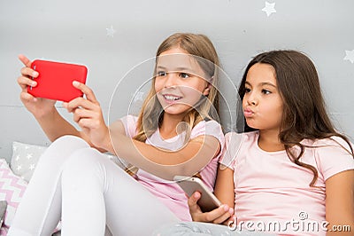 Kids taking selfie in bedroom. Pajamas party concept. Girlish leisure happy childhood. Girls long hair with smartphones Stock Photo