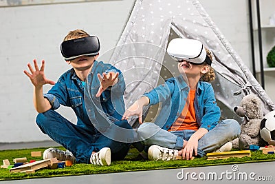 kids using virtual reality headsets and gesturing by hands near wigwam Stock Photo