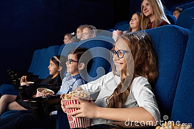 Kids watching movie in cinema, holding popcorn buckets. Stock Photo