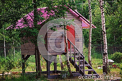 Kids wooden tree house with pink roof in summer forest Stock Photo