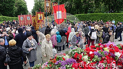 In Kiev`s Glory Park, many people bring flowers to the monument on Victory Day. A procession of people with Orthodox banners runs Editorial Stock Photo