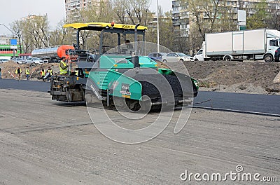 KIEV, UKRAINE - APRIL 6, 2017: Workers operating asphalt paver machine and heavy machinery during road repairs Editorial Stock Photo