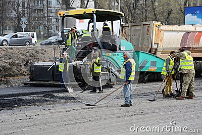 KIEV, UKRAINE - APRIL 6, 2017: Workers operating asphalt paver machine and heavy machinery during road repairs Editorial Stock Photo