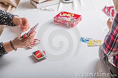 Kiev, Ukraine - Jeniaury 31th 2020 : Uno cards in female senior hand and little child boy; American card game Editorial Stock Photo