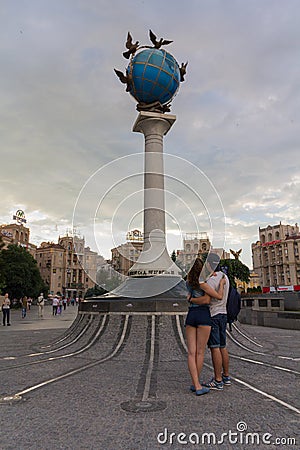 Kiev, Ukraine - June 16, 2016: Young couple with a monument with a globe Editorial Stock Photo