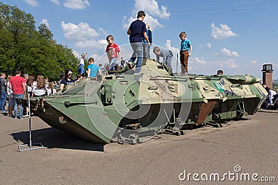 Kiev, Ukraine - May 09, 2016: Children are playing on a damaged armored personnel carrier Editorial Stock Photo