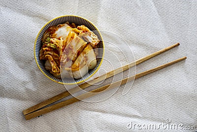 Kimchi in plate with chopsticks on light fabric Stock Photo