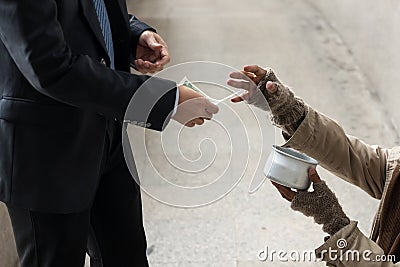 Kind businessman giving one dollar bill money to beggar or homeless guy Stock Photo