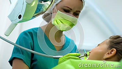 Kind dentist drilling teenage girl tooth, professional pediatric stomatology Stock Photo