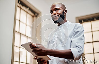The kind of gadget that facilitates great designs. a young businessman using a digital tablet in a modern office. Stock Photo