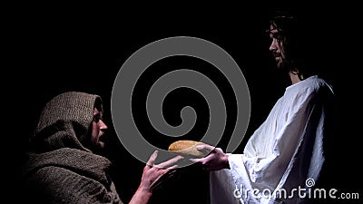 Kind Jesus in crown of thorns giving bread for hungry homeless man, miracle Stock Photo