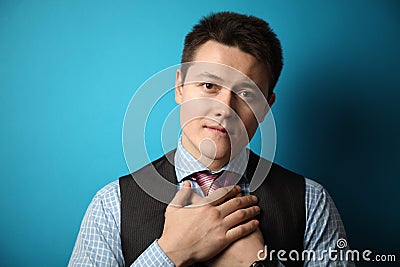 Kind look of a young man in a suit on a blue background. Prayer and redemption of gruhs. Donation Stock Photo
