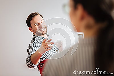 Kind man pointing to his colleague while visiting interesting workshop Stock Photo