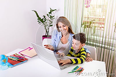 Kind mother helping her son doing homework online. Mother Helping Son With Homework during Covid-19 Coronavirus and Learning from Stock Photo