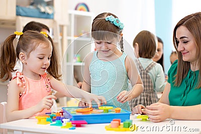 Kindergarten teacher and children playing toy sorter in daycare centre Stock Photo