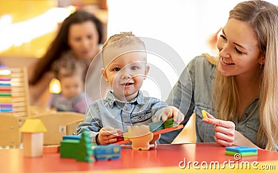 Kindergarten teacher playing with kid in nursery. Developmental toys for preschool. Stock Photo