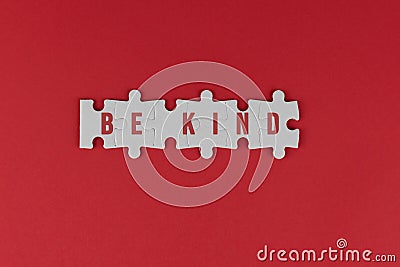Kindness inspirational words - Be kind. With text on white puzzle jigsaw on red background. Humanity concept. Stock Photo