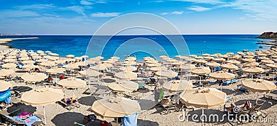 Kiotari beach with umbrellas and holiday-makers in village of K Stock Photo