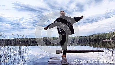Kirov, Russia - April 29, 2023: Girl or woman walks along old wooden pier, with lake in background during evening and Editorial Stock Photo