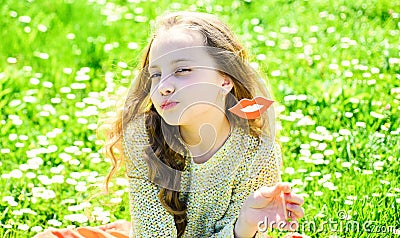 Kiss concept. Girl on kissing face spend leisure outdoors. Girl sits on grass at grassplot, green background. Child Stock Photo