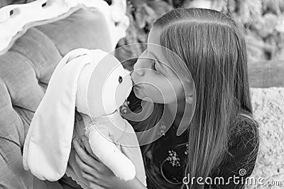 A kissable cutie. Small girl kiss rabbit toy. Little girl with cute bunny at Christmas tree. Little child play with soft Stock Photo