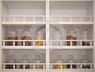 Kitchen cabinet with open shelves, on which there are glass jars with spices, cereals and seasonings Stock Photo